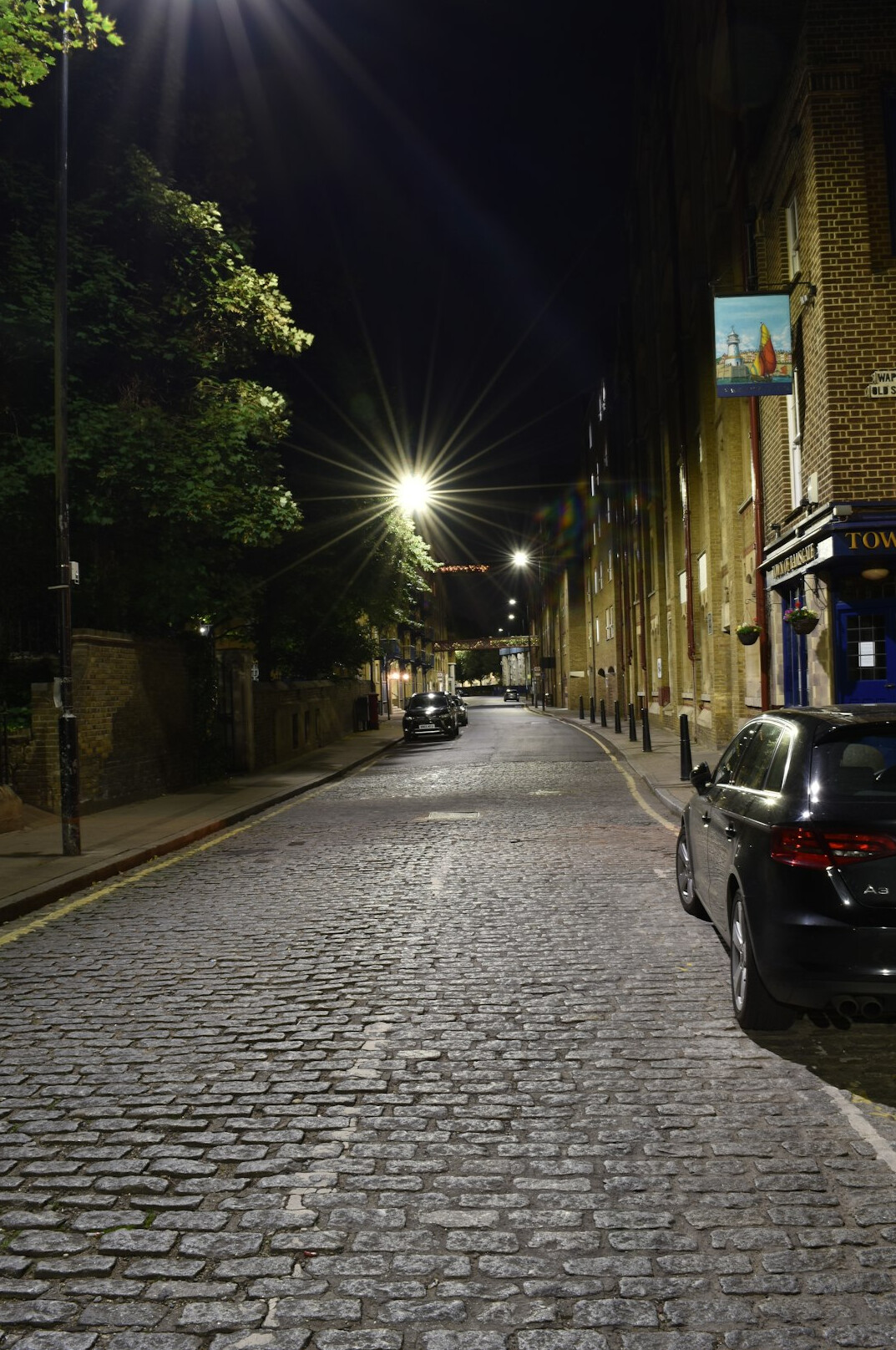 Empty cobblestone street at night under a streetlight